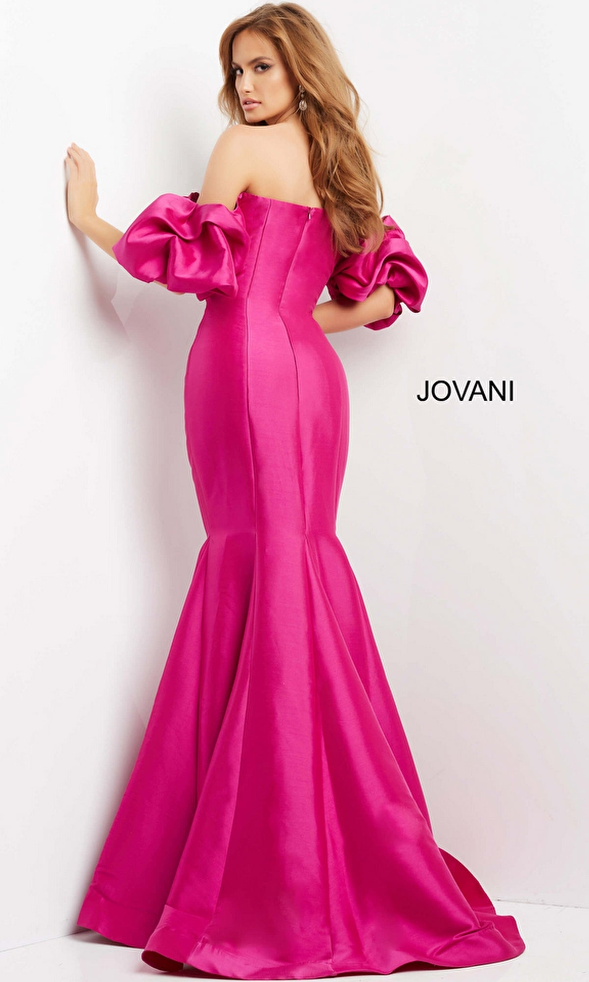A woman poses against a white background in a bright pink, off-the-shoulder Jovani Puff-Sleeve Long Mermaid Prom Dress 09031, featuring puffy sleeves. The word